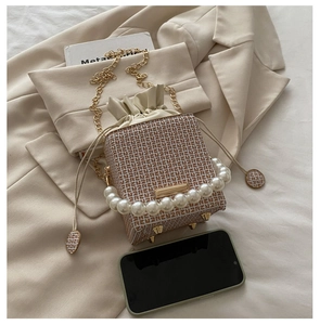 Detail einer Mini-Beuteltasche mit Perlenhenkel, Goldkette und Monogramm-Musterung