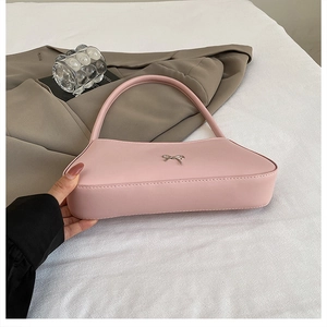 Close-up of pink faux leather shoulder bag featuring a silver bow buckle and zip closure