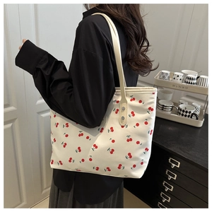 Detail of cherry print canvas tote bag featuring reinforced metal rivets and slim straps