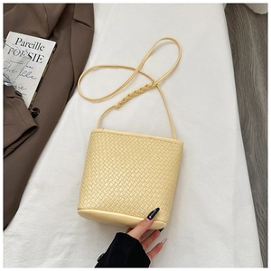 Close-up of woven leather texture on a beige bucket bag with detailed shoulder strap