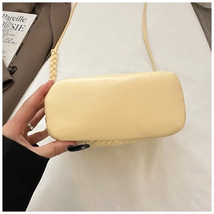 Detail of cream yellow bucket bag showing the woven strap and rectangular base design