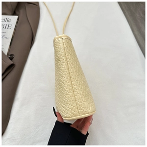Detail view of woven leather texture on cream-colored crossbody bucket bag with strap