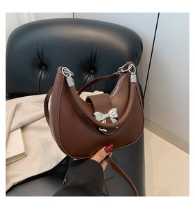 Close-up of matte dark brown half-moon bag with a silver metal bow accent