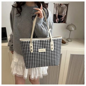 Close-up of houndstooth tote bag with cream leather trim and fashion logo detail