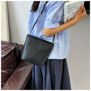 Detail of hand-woven black leather crossbody bag with minimalist shoulder strap style