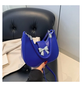 Detail of royal blue crescent bag with silver bow buckle and PU leather texture
