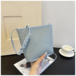 Detailed view of light blue woven texture and braided strap on minimalist bucket bag