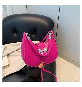 Detailed view of magenta underarm bag with silver bow buckle and smooth PU leather