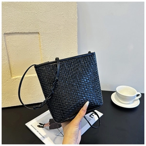 Detail of black woven leather bucket bag featuring a cross-weave texture and fine strap