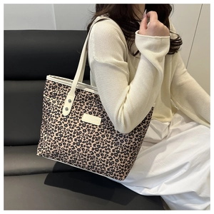 Leopard print tote bag detail showing cream white synthetic leather handles and logo patch