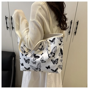 Detail of white tote bag with black butterfly print and leather fashion label