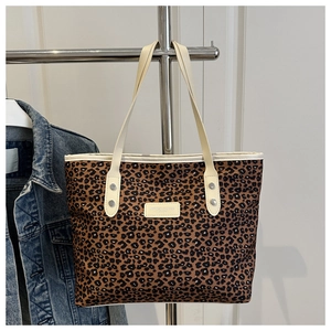 Detailed view of leopard print tote bag with white handle and metal rivet reinforcement