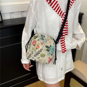 Floral drawstring bucket bag with adjustable shoulder strap shown on a model