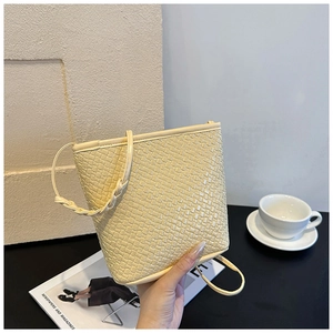 Detail of cream woven bucket bag showing intricate leather texture and braided strap