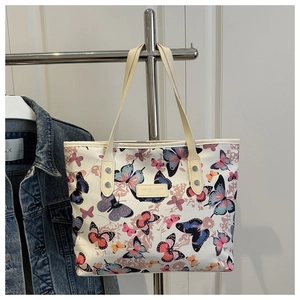 Close-up of large cream tote bag with colorful butterfly prints and decorative rivets