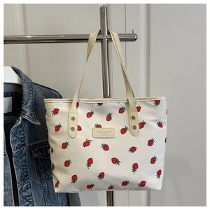 Detail of strawberry print tote bag featuring metallic rivets and fashion leather patch