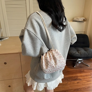 Schultertasche im Blumenmuster mit Kordelzug aus weißem Canvas an einem Model getragen