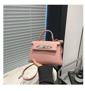 Detail of light pink woven texture handbag featuring gold rotary lock and top handle