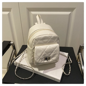 Detailed shot of white quilted leather mini backpack with metal chain strap on a chair