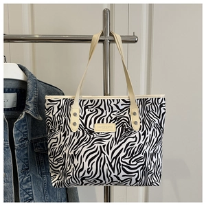 Detail of zebra print tote bag with cream leather handles and fashion logo patch