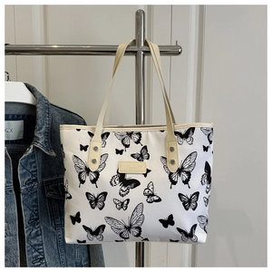 Close-up of butterfly print tote bag with leather handles and metal rivet details