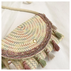 Detail of woven straw saddle bag featuring multi-color stitching and hanging tassels