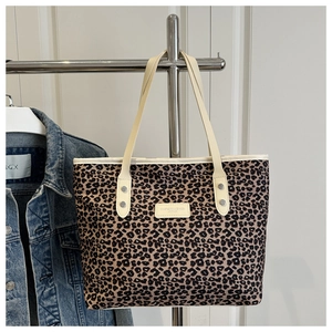 Detail of leopard print tote bag with cream handles and silver rivet logo plaque