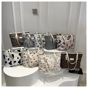Assorted patterned tote bags including leopard and floral prints on white podiums