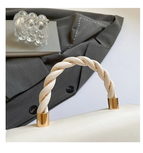 Close-up of white leather handle with gold metallic chain twisted rope detail