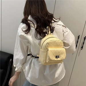 Quilted beige mini backpack with gold chain straps and metal lock shown on model