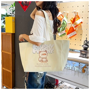 Detail view of large cream canvas tote bag with cute animal print and plush text design