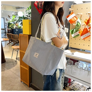 Detailed close-up of grey corduroy tote bag featuring a vintage rectangular fabric label