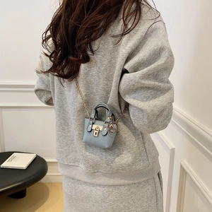 Hellblaue Mini-Umhängetasche aus Leder mit goldenem Schloss und Kette am Frauenmodell