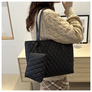 Détail d'un grand sac cabas noir matelassé avec une petite pochette assortie sur l'épaule