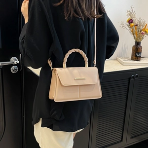 Minimalist beige crossbody handbag with twisted top handle and metallic buckle detail