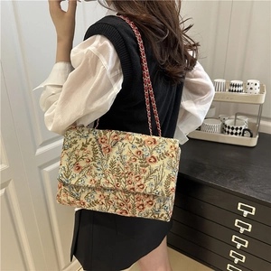 Vintage floral tapestry shoulder bag with red metal chain strap shown on a model