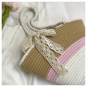 Macro detail of tricolor woven beach tote bag with a beige lace bow and cotton rope handle