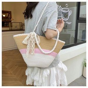 Detail of tri-color woven tote bag with a large white lace bow and rope handles