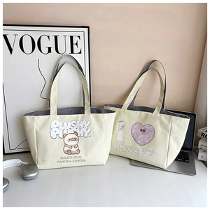 Close-up of beige canvas tote bags with cute panda print and plushy slogan text