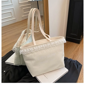 Gros plan du sac cabas en toile blanche avec bordure en dentelle et lettrage minimaliste