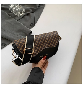 Detail of vintage saddle bag with black-brown pattern and adjustable fabric strap