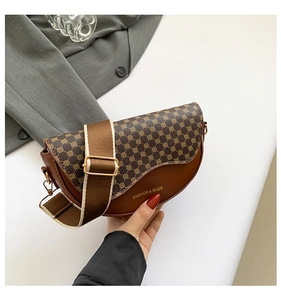 Close-up of brown saddle bag with geometric pattern flap and striped textile strap