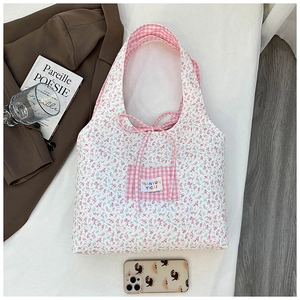 Detail of floral canvas tote bag featuring pink gingham pocket and tie bow closure