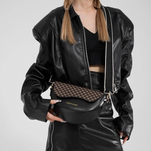 Vintage leather saddle bag with geometric pattern and wide contrast strap worn by model