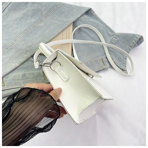 Detail of white glossy mini square bag showing silver metal buckle and slim shoulder strap
