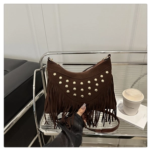 Detail of dark brown suede crossbody bag featuring gold rivets and long tassels