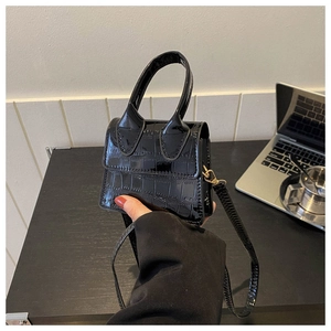 Detailed view of mini black crocodile embossed patent leather handbag with top handle strap