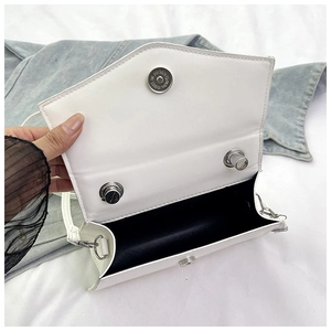 Detail of the white leather crossbody bag showing the silver magnetic clasp and black interior