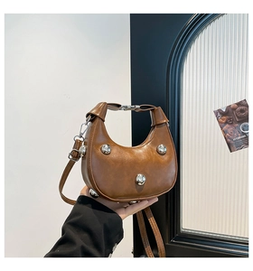 Dettaglio di una borsa hobo marrone con sfere metalliche argentate e tracolla rimovibile