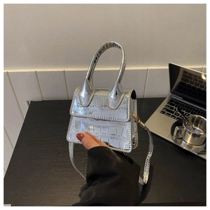 Macro detail of silver mini bag featuring crocodile texture and sleek top handle